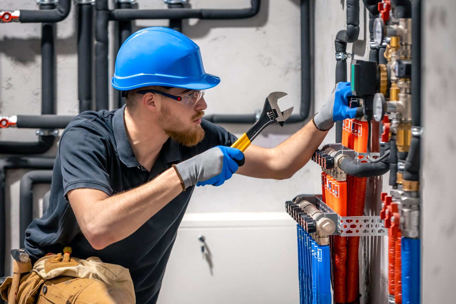 Technician using a wrench to service insulated mechanical pipes and valves